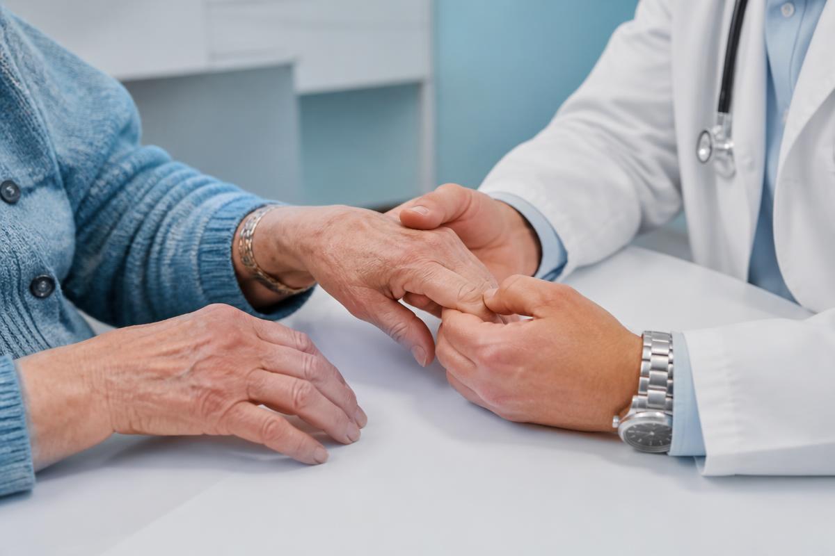 Manos de paciente con artritis examinadas por un médico